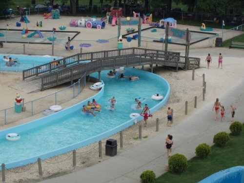 A water park scene with a lazy river, kids playing, and colorful attractions in the background.