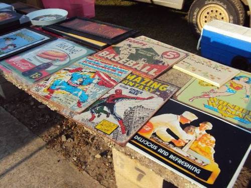 A table displaying various vintage signs and posters, including comic art and food advertisements.