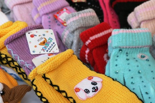 Colorful knitted socks with various patterns and designs, including animal faces and embellishments, displayed together.