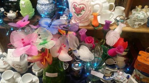 Colorful artificial flowers in various shapes and sizes, displayed among decorative items and soft blue lights.