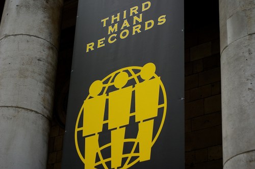 Sign for Third Man Records featuring three stylized figures and a globe design in yellow on a black background.