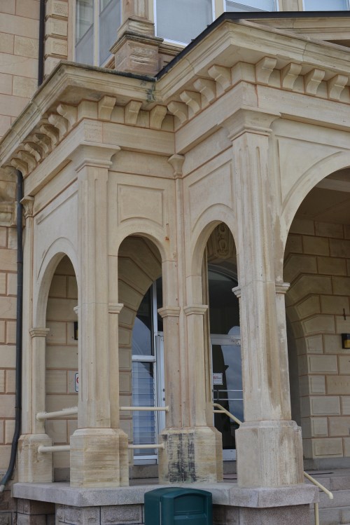 Architectural detail of a building featuring arched columns and a textured stone facade.