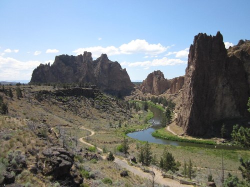 A scenic view of a winding river surrounded by rocky cliffs and sparse vegetation under a clear blue sky.