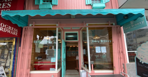 A colorful storefront with pink walls and teal accents, featuring large windows and an awning labeled "Easy Breezy."