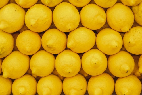 A close-up view of a uniform arrangement of bright yellow lemons stacked closely together.