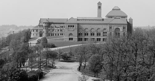 Historic building on a hillside, featuring intricate architecture and surrounded by trees and a winding road.