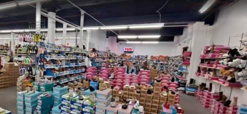 A spacious retail store filled with shelves of shoes and boots, organized in colorful boxes and displays.