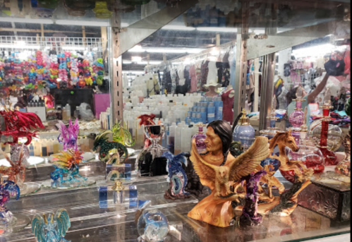 Colorful glass figurines of dragons, horses, and other creatures displayed in a shop, with various products in the background.