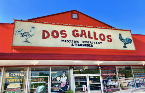 Sign for "Dos Gallos Mexican Restaurant & Taqueria" on a bright red building, featuring roosters and colorful storefront.