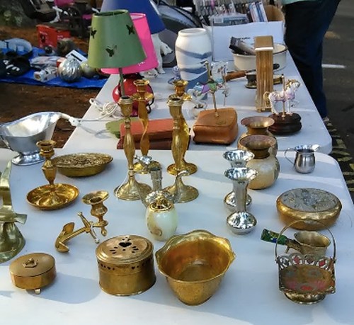 A variety of vintage items and decorative objects displayed on a table, including candlesticks, lamps, and small containers.
