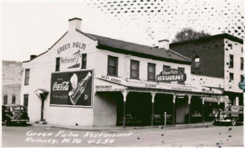 Black and white photo of the Green Palm Restaurant in Romney, W.Va., featuring vintage signage and classic cars.