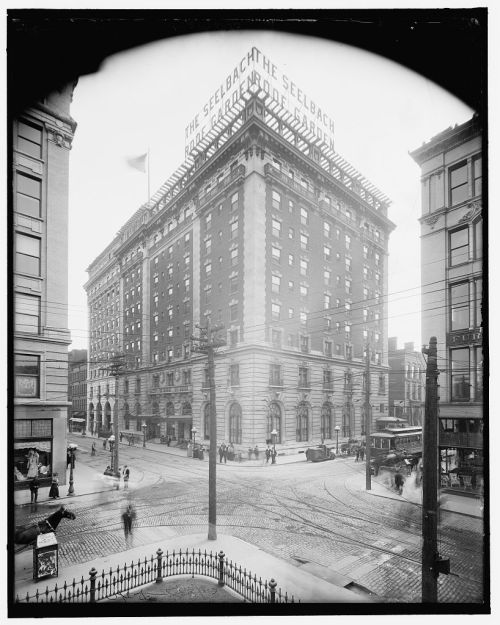 Historic view of the Seelbach Hotel, featuring streetcars and pedestrians in a bustling urban setting.