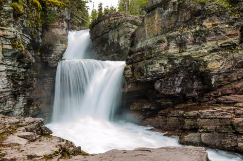A serene waterfall cascading over rocky cliffs, surrounded by lush greenery and a tranquil atmosphere.