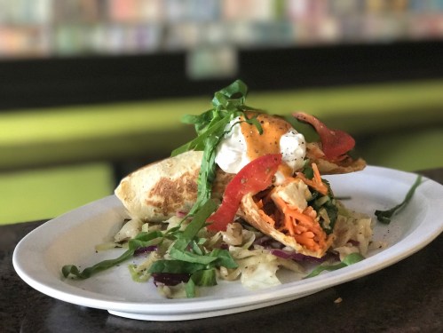 A plate of tacos filled with chicken, topped with lettuce, tomatoes, sour cream, and served on a bed of cabbage.