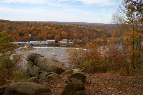 Scenic view of a river surrounded by autumn foliage and rocky terrain under a clear sky.