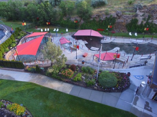 Aerial view of a landscaped park featuring red canopies, water features, and walking paths surrounded by greenery.