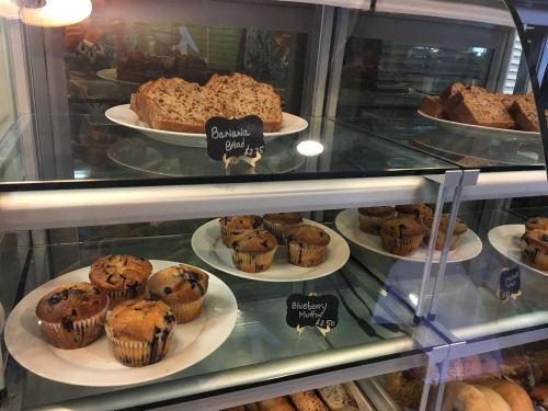 Display case with banana bread slices and blueberry muffins, each labeled with prices.