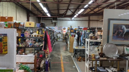 A spacious indoor market filled with various items for sale, including clothing, decor, and antiques.