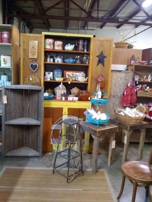 A vintage display featuring wooden shelves, colorful teapots, and decorative items in a rustic shop setting.