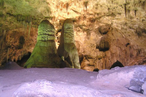 Stalactites and stalagmites in a dimly lit cave, showcasing unique rock formations and textures.