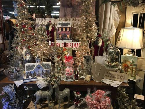 A festive display featuring Christmas decorations, trees, and ornaments on a table, creating a cozy holiday atmosphere.