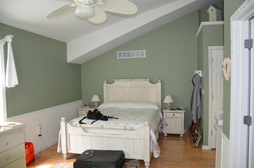 A cozy bedroom with a sloped ceiling, featuring a bed, nightstands, and light green walls.