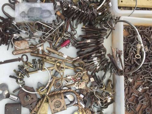 A cluttered assortment of various keys, locks, and metal hardware pieces scattered on a surface.
