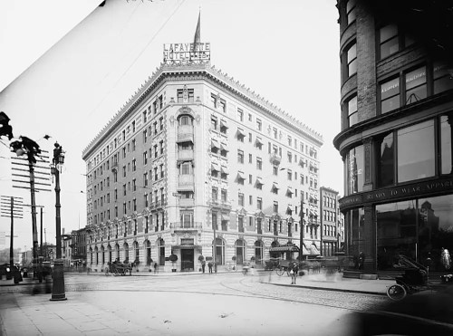 Historic black-and-white photo of the Lafayette Hotel, featuring streetcars and early 20th-century architecture.