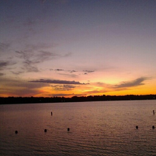 A serene sunset over a calm lake, with colorful clouds reflecting on the water's surface.