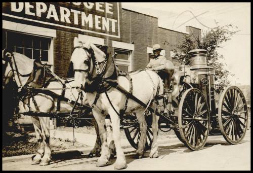 A historical black-and-white photo of a horse-drawn wagon parked near a sign for the Refugee Department.