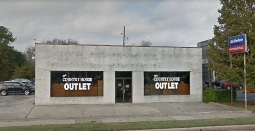 A storefront with large windows displaying "Country House Outlet" signage, set in a suburban area.