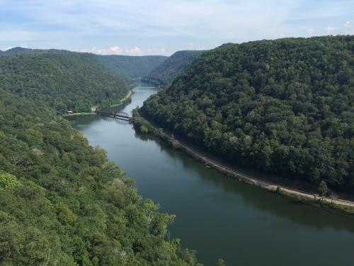 A scenic view of a winding river surrounded by lush green hills under a clear blue sky.