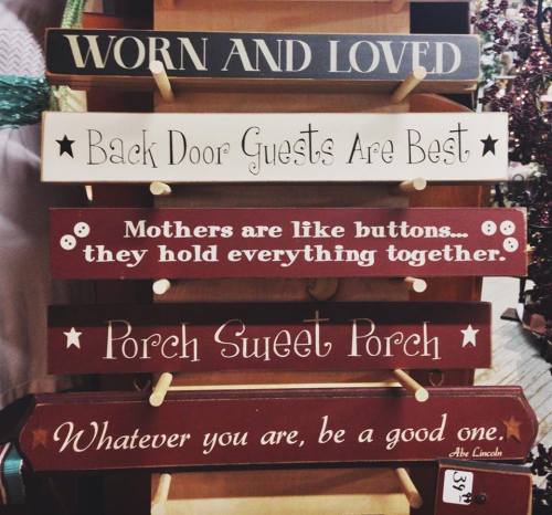 A display of decorative wooden signs with various inspirational and welcoming phrases.