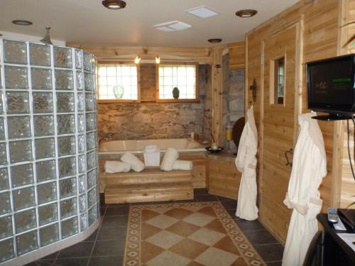 A cozy bathroom featuring a glass block shower, wooden accents, a soaking tub, and plush robes.