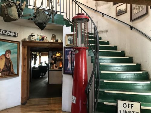 A vintage gas pump stands beside a spiral staircase leading to an upper level, adorned with photos and memorabilia.