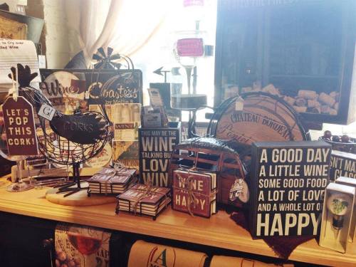 A display of wine-themed decor and accessories, including signs, cork holders, and decorative bottles.