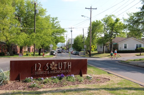 Sign for 12 South District & Neighborhood, with trees and houses lining the street in a sunny setting.