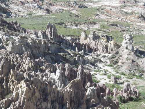 A colorful, rugged landscape featuring unique rock formations and green vegetation in a dry, mountainous area.