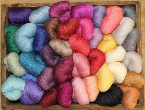 A wooden box filled with colorful skeins of yarn in various shades, including purple, pink, blue, and yellow.