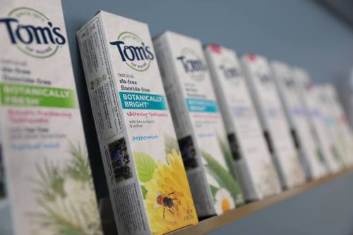 A shelf displaying various Tom's natural toothpaste boxes with colorful labels and botanical designs.