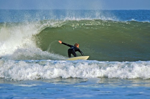 A surfer rides a large wave, skillfully maneuvering on a surfboard in the ocean.