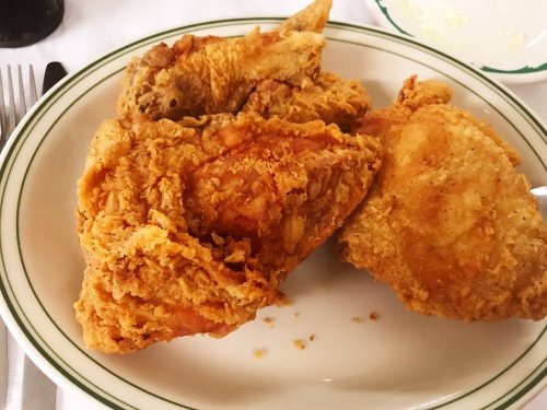 A plate of crispy fried chicken pieces, golden brown and served on a white dish with a green rim.