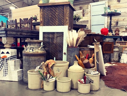 A collection of vintage pottery, wooden items, and rustic decor arranged in a cozy market setting.