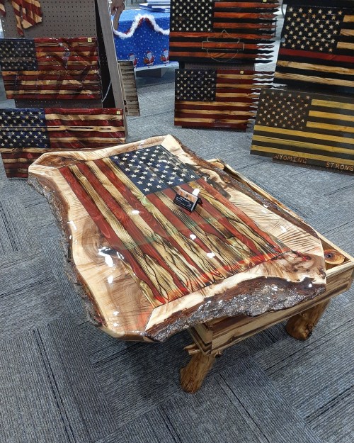A wooden table featuring a carved American flag design with a glossy finish and natural edges.