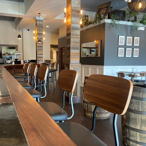 Interior of a cozy restaurant with wooden bar stools, a polished counter, and warm lighting.