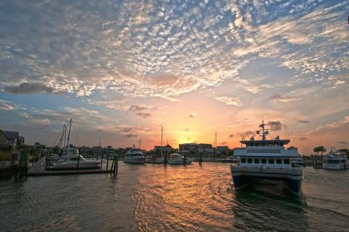 A serene harbor at sunset, with boats docked and colorful clouds reflecting in the water.