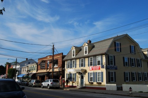 A charming street scene featuring historic buildings, shops, and a clear blue sky.