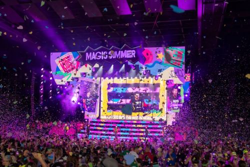 A vibrant concert scene with a colorful stage, confetti falling, and a large crowd enjoying the performance.