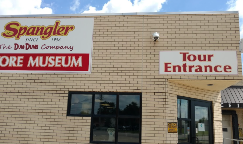 Exterior of the Spangler Store Museum with a sign for the tour entrance. Bright blue sky in the background.