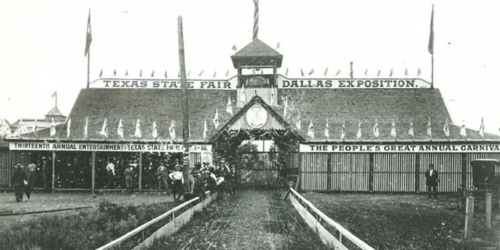 Historic black-and-white photo of the Texas State Fair entrance, featuring flags and a large sign for the annual event.
